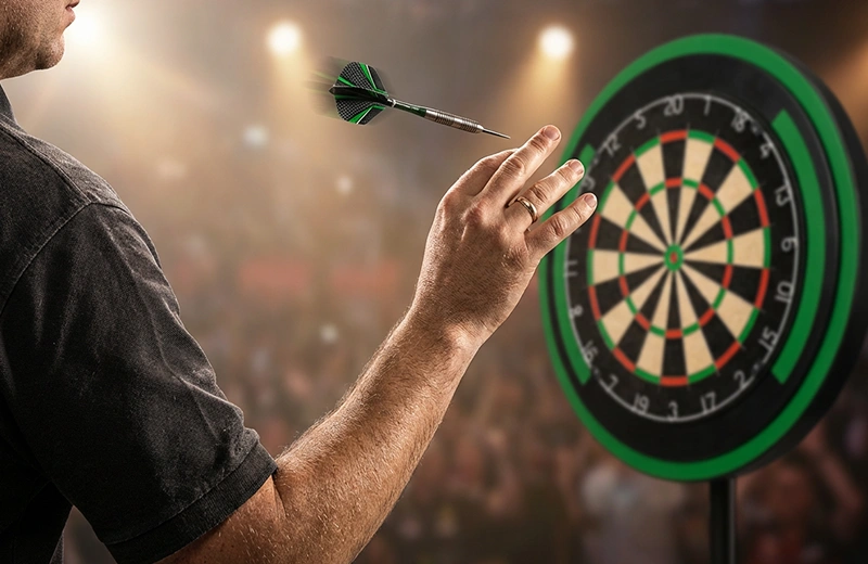 Darts-Spieler beim konzentrierten Pfeilwurf auf die Dartscheibe in Nahaufnahme